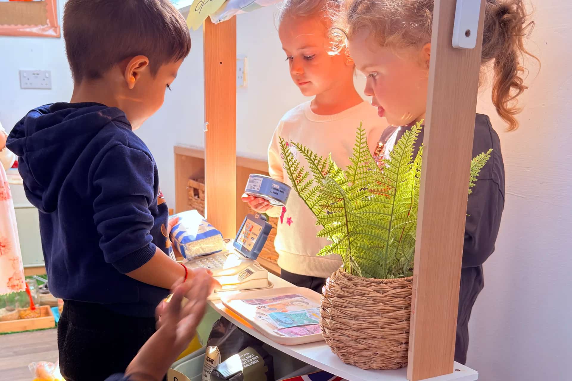 Children exploring the role-play farm shop at Blue Nest Montessori Borehamwood