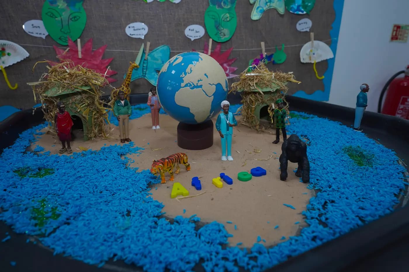 Africa-themed cultural sensory bin with globe and figurines at Blue Nest Borehamwood