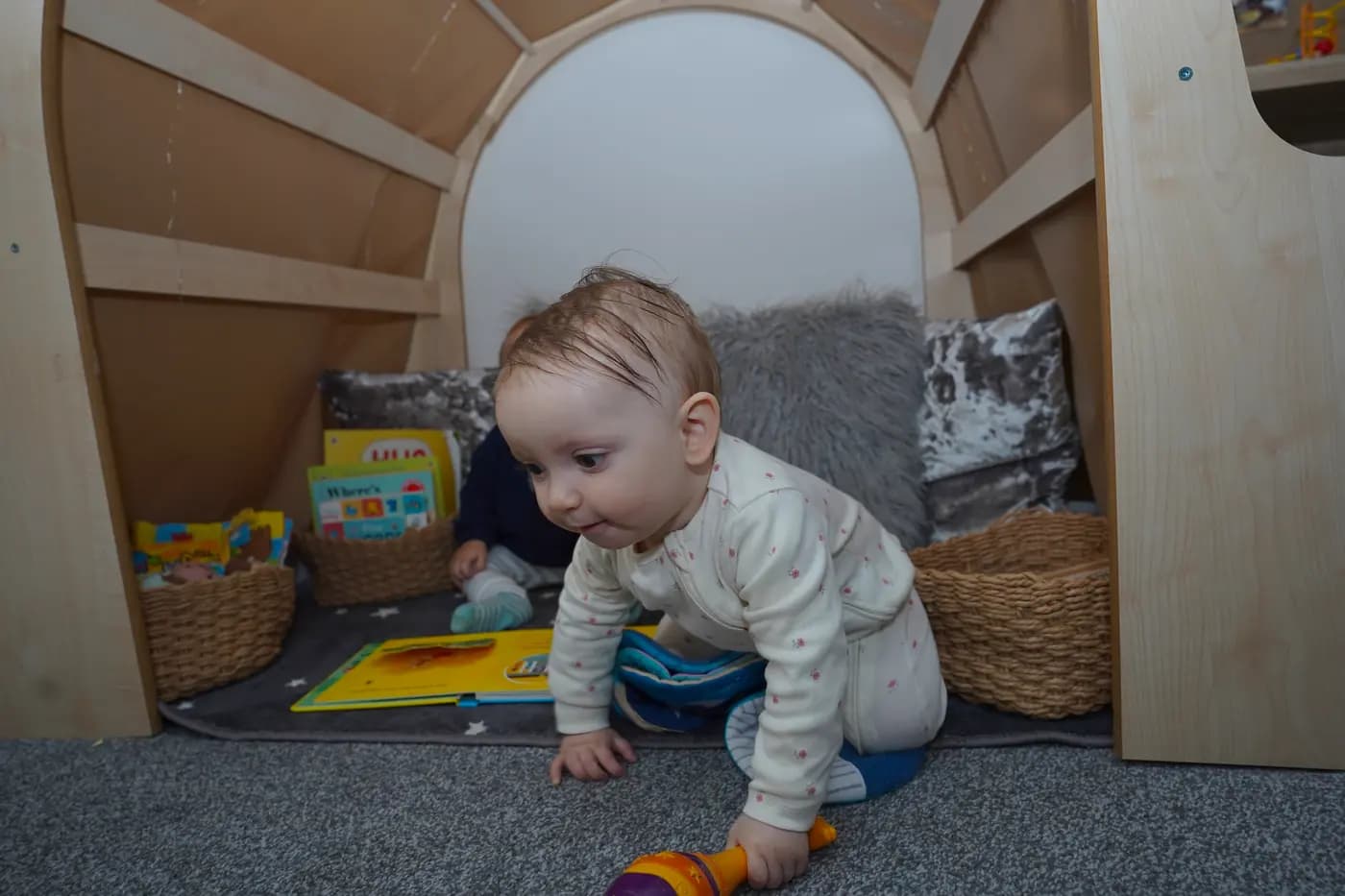 Baby exploring the wooden reading arch at Blue Nest Borehamwood