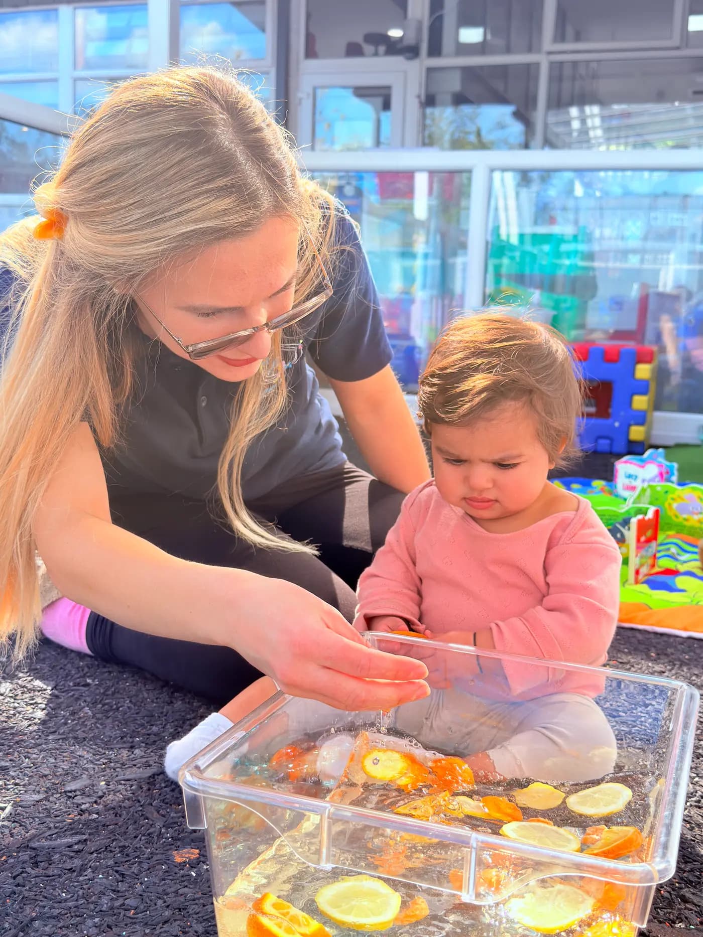 Teacher and toddler exploring a citrus water sensory tray at Blue Nest Montessori Harrow