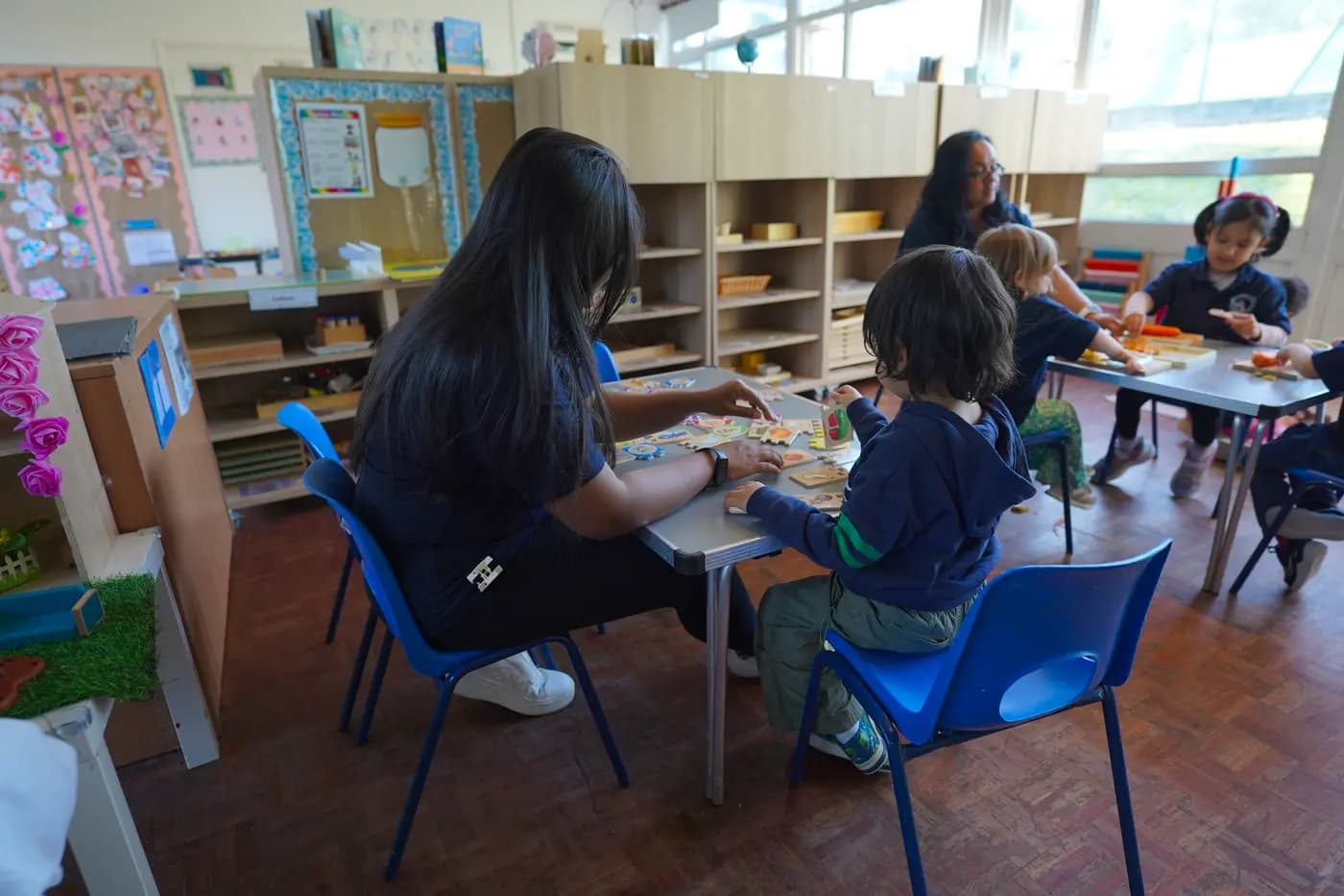 Blue Nest Pinner teacher working one-to-one with a child on a Montessori puzzle