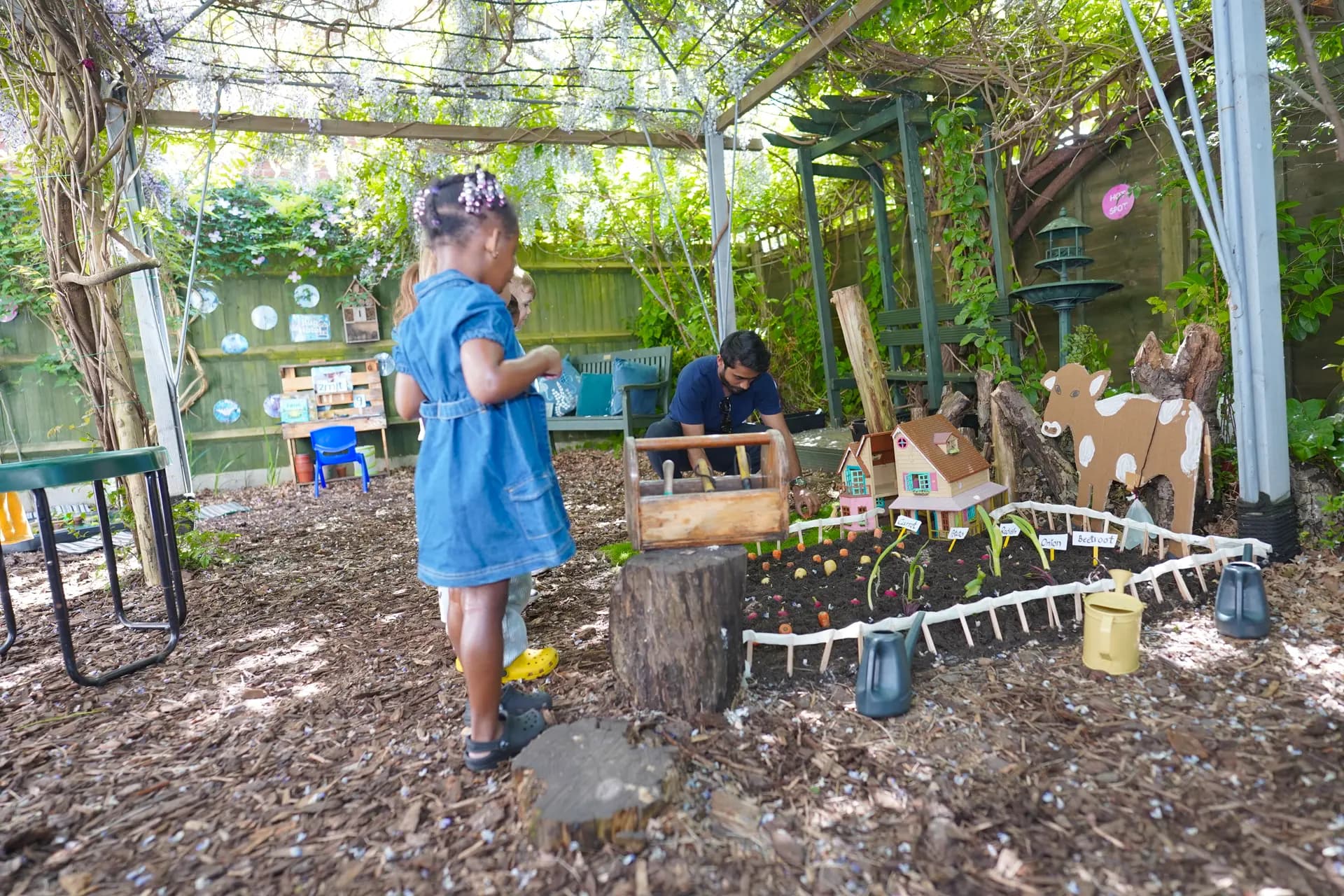 Children playing with a wooden village in the Blue Nest Pinner garden